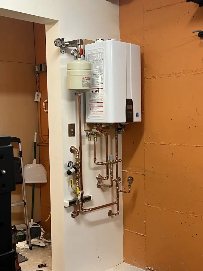 Plumbing technician inspecting water heater connections in Wasco